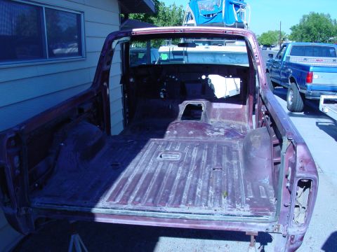 1979 Ford Bronco - The body shell of a 1979 Ford Bronco is shown from the rear, with another Ford truck in the background.