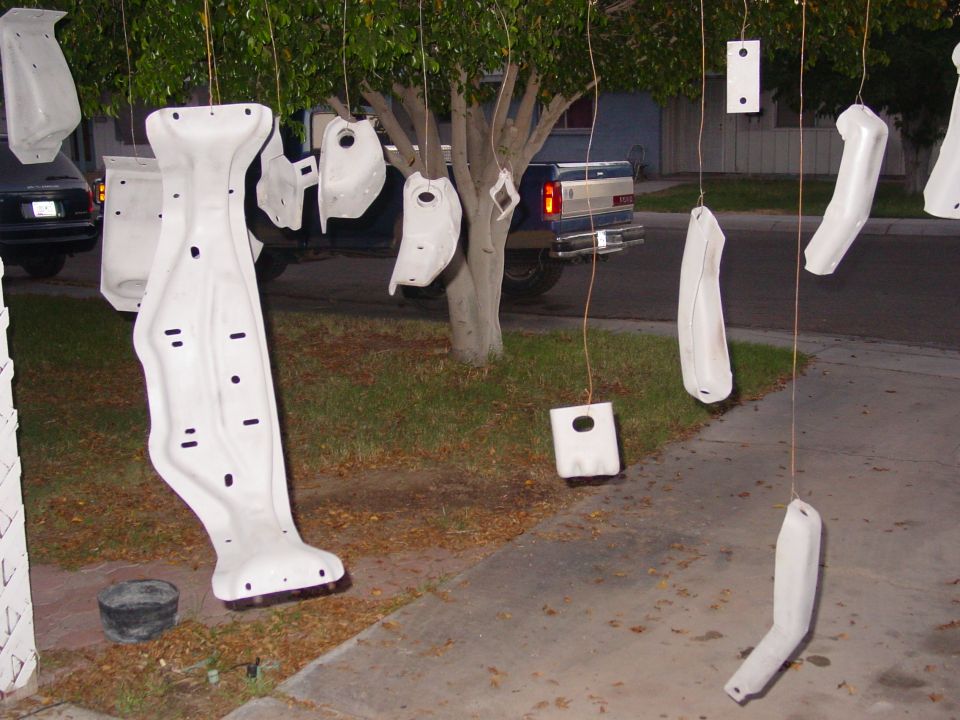 Car parts hanging from a tree to dry, with a blue pickup truck in the background