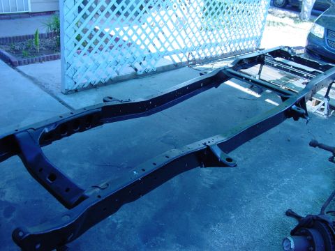 1979 Ford Bronco - A bare vehicle frame sits on a driveway, awaiting restoration.