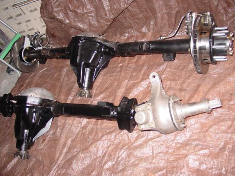 1979 Ford Bronco - Two vehicle rear axles are shown, one black and one silver, on a brown tarp.