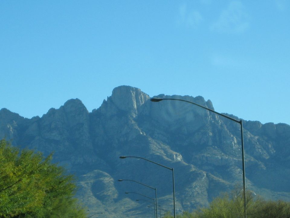 Mountain range under a clear blue sky with several streetlights in the foreground
