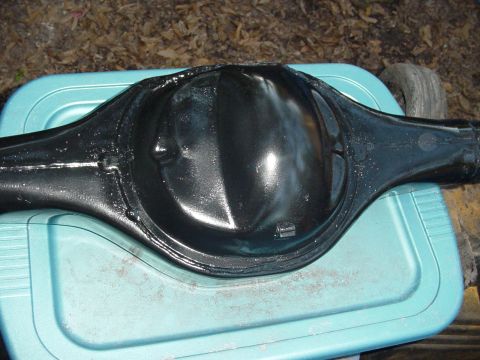1989 Ford Bronco - A black rear differential housing is shown resting on a teal plastic surface, with a tire visible in the background.