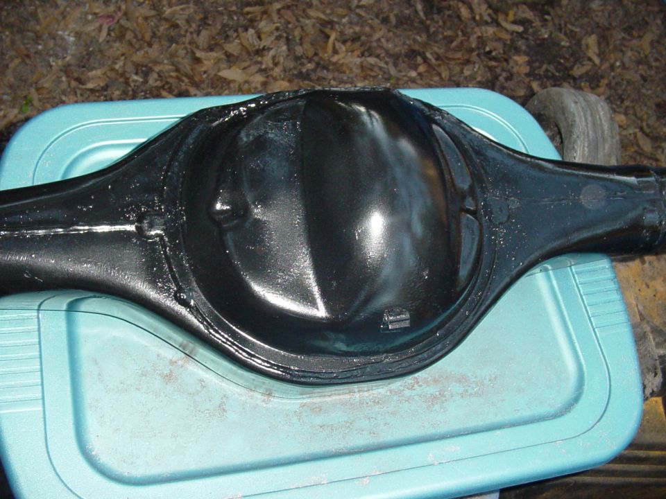 Gloss black painted solid axle housing resting on a teal cooler lid