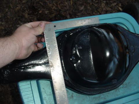 1989 Ford Bronco - A ruler measures the diameter of a black rear axle differential housing, likely for a vehicle part replacement or modification.