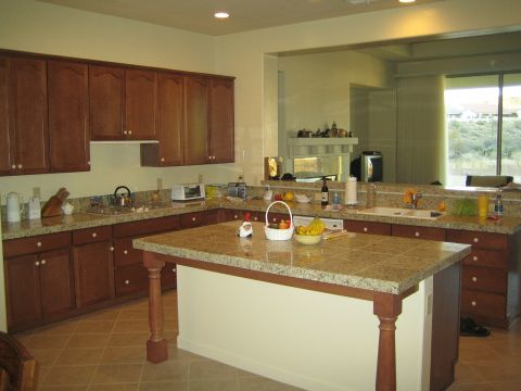 1968 Ford Mustang - A spacious kitchen features dark wood cabinetry and a large granite-topped island with a fruit basket.
