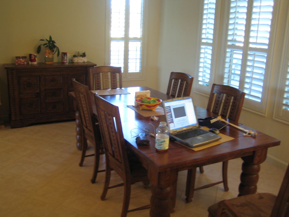 Dining room table with chairs, a laptop, and a sideboard