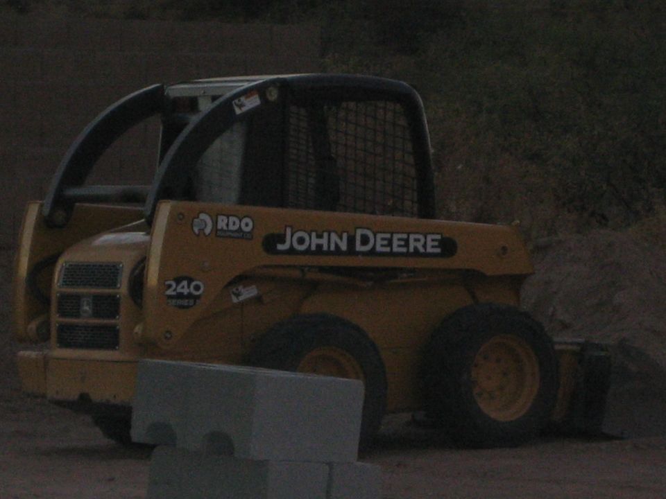 Yellow John Deere skid steer loader, 3q-front view