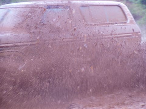 1978 Ford Bronco - This vehicle is covered in mud as it drives through a muddy area, creating a large splash.