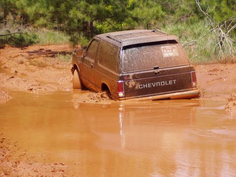1978 Ford Bronco - This Chevrolet SUV is deeply stuck in a muddy puddle, with a 'For Sale' sign visible on the rear window.