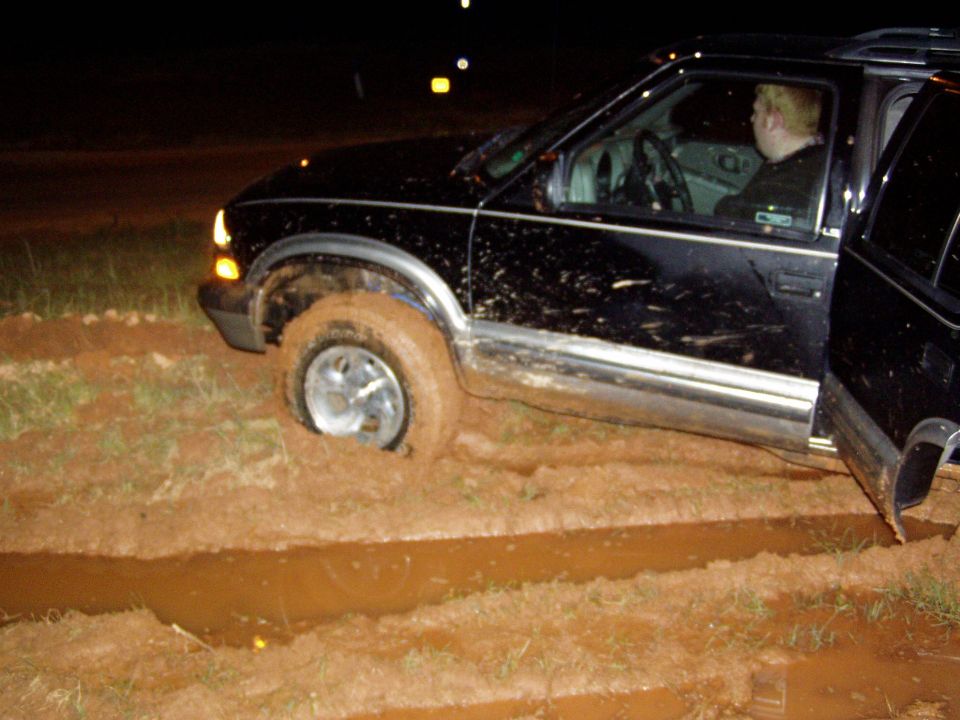 Black SUV stuck in mud with driver inside