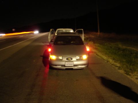 1992 Ford Taurus - Two cars stopped on the side of the road at night, one with its doors open.