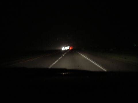 1992 Ford Taurus - View from inside a vehicle driving on a highway at night, with other cars ahead.