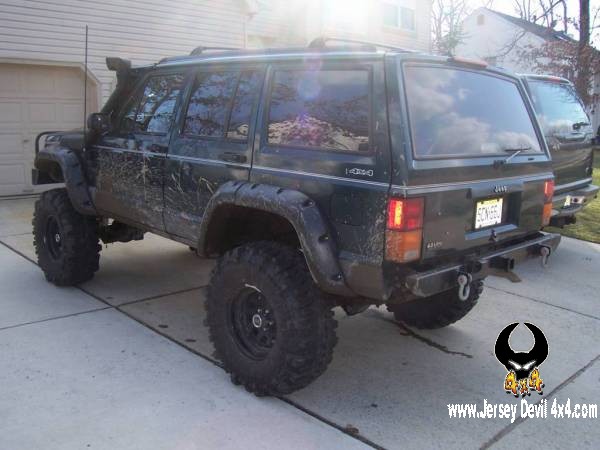 Dark green Jeep Cherokee XJ with snorkel, fender flares, and large tires, parked on a driveway