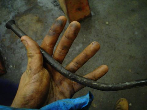1966 International School Bus - A hand holds a metal rod, possibly a part from an engine or vehicle.