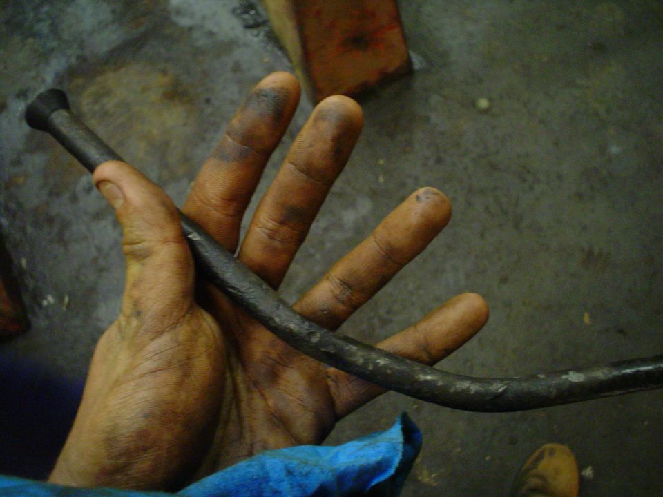 Dirty hand holding a curved metal rod