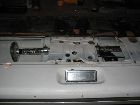 1995 Ford Bronco - The interior of a vehicle's tailgate shows two foil-wrapped rods secured by clamps.