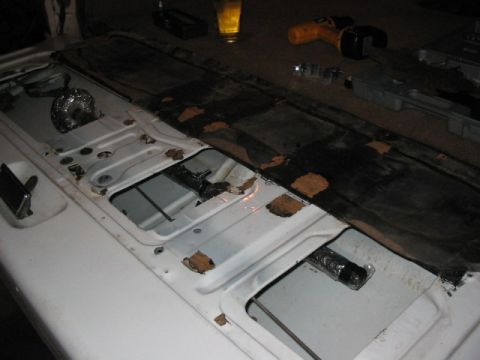 1995 Ford Bronco - The interior of a white vehicle's tailgate reveals rust damage and exposed metal, with visible storage compartments.