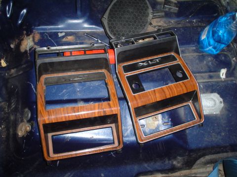 1984 Ford Bronco - Two XLT trim pieces, likely for a Ford truck or SUV, are shown laid out on a blue interior floor during a rebuild.