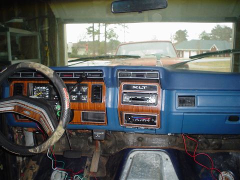 1984 Ford Bronco - The interior of a 1980s Ford truck shows an aftermarket stereo and a camouflage steering wheel cover.
