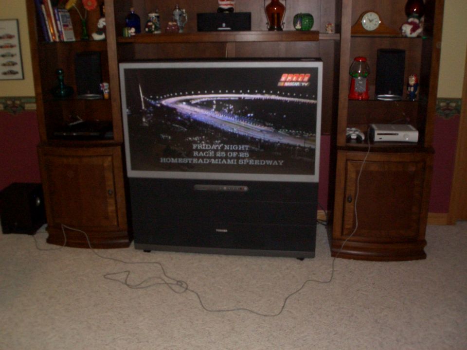 Rear-projection TV in a wood wall unit showing a NASCAR broadcast graphic