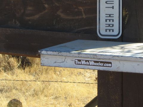 1968 Ford Mustang - Toolbox with a sticker is mounted on a wooden post near dry grass and barbed wire.