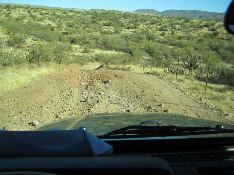 1968 Ford Mustang - Driving on a rough, unpaved road through a dry, arid environment under a clear blue sky.