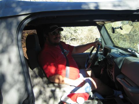 1968 Ford Mustang - A man is driving a Jeep, wearing a red shirt and a baseball cap.