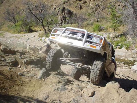1989 Ford Bronco - An off-road SUV tackles a challenging rocky path, demonstrating its suspension and tire grip.