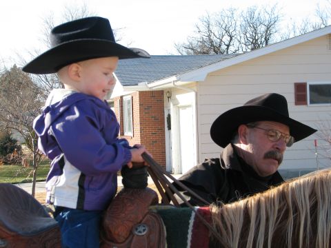 1982 Ford Bronco - A child and an adult, both wearing cowboy hats, are on horseback in front of a house.