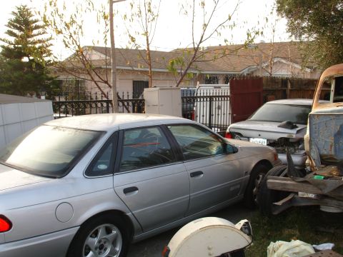 1992 Ford Taurus - A silver 1992 Ford Taurus sedan is parked in a yard with other vehicles.