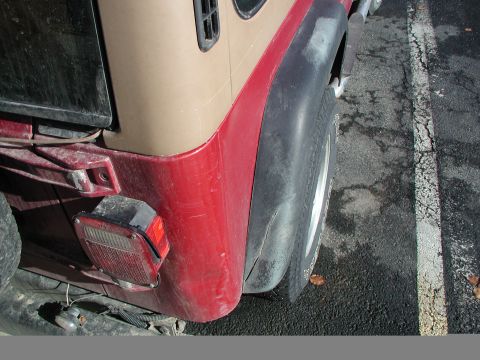 1998 Jeep TJ - Rear view of a Jeep Wrangler showing the quarter panel, taillight, and tire. The vehicle has a two-tone paint scheme.