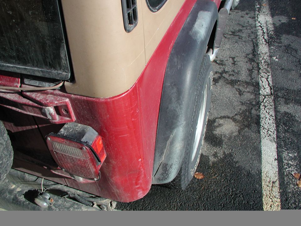 1997 Jeep Wrangler rear quarter panel, taillight, and tire. Two-tone paint with tan top and red lower body