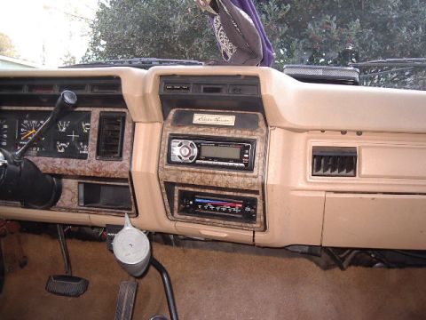 1985 Ford Bronco - The interior of a 1985 Ford Bronco shows its dashboard with wood grain accents and dual-DIN stereo system.