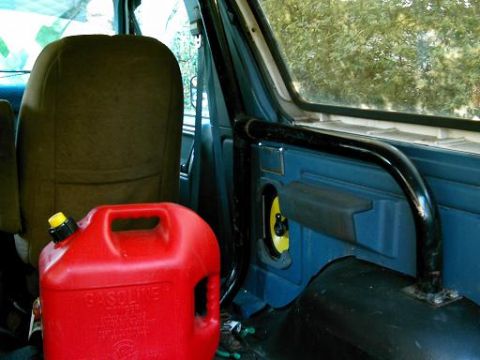 1986 Ford Bronco - A red gas can sits next to the seat inside a vehicle, with a black roll bar visible.