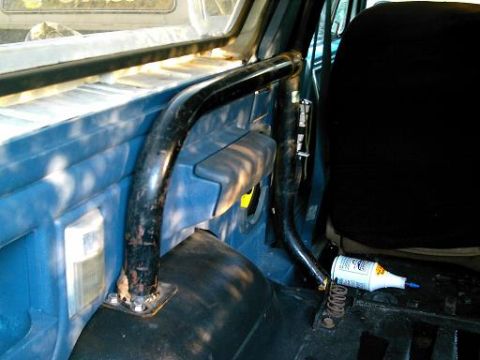 1986 Ford Bronco - Roll bar installed inside a vehicle's interior, showing blue paneling and a black seat.