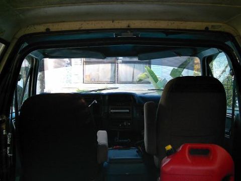 1986 Ford Bronco - The interior of a vehicle is shown, with a focus on the dashboard and seats, and a red gas can in the foreground.