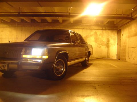1988 Ford Crown Victoria LTD - A 1988 Ford Crown Victoria LTD is seen parked in a dimly lit garage with its headlights on.