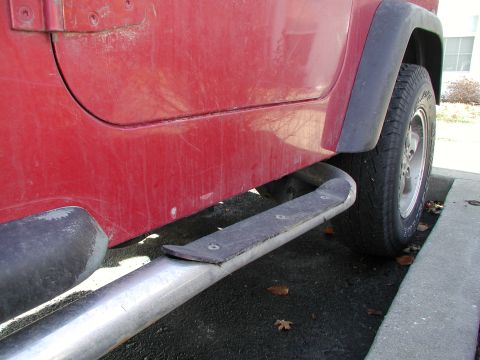 1998 Jeep TJ - Side view of a red Jeep TJ showing its running board and tire.