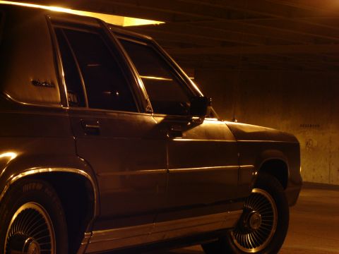 1988 Ford Crown Victoria LTD - A 1988 Ford Crown Victoria LTD is seen from the side in a dimly lit area.