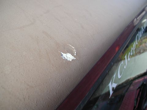 1998 Jeep TJ - Close-up of a paint chip on a vehicle's roof, with a 'KC Jeep Club' sticker visible on the side window.