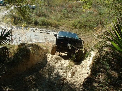 1995 Ford Bronco - Ford Bronco tackling a challenging muddy obstacle on an off-road course.