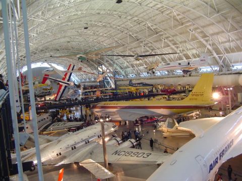1994 Ford Bronco - A vast museum hall displays numerous aircraft suspended from the ceiling and on the floor, with a prominent yellow Boeing 707 in the mid-gr…