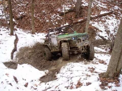 1992 Ford Bronco - Off-road vehicle attempts to navigate a muddy, snowy trail in a wooded area.