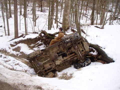 1992 Ford Bronco - An off-road vehicle has overturned in a snowy ditch, with a person still inside the cab.