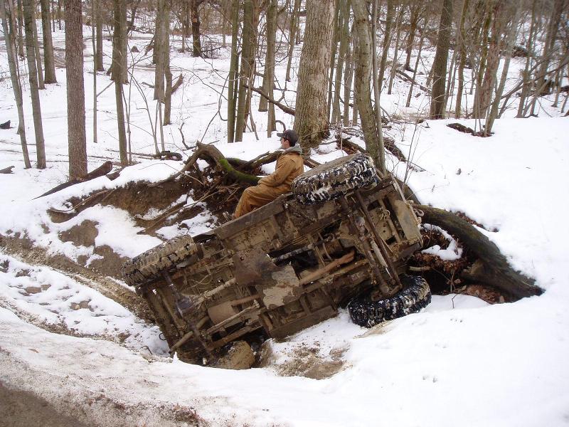 Off-road vehicle overturned in snow with driver sitting in cab