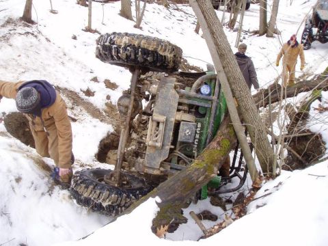 1992 Ford Bronco - An ATV has overturned in a snowy wooded area, with several people observing the scene.
