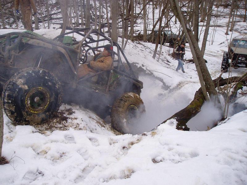 Off-road buggy with roll cage navigating snowy terrain, emitting steam