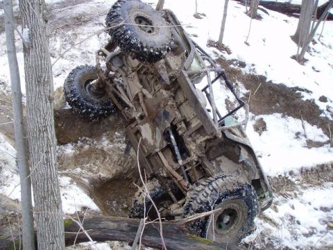 1992 Ford Bronco - This off-road vehicle is stuck in a muddy, snowy ditch, tilted on its side.
