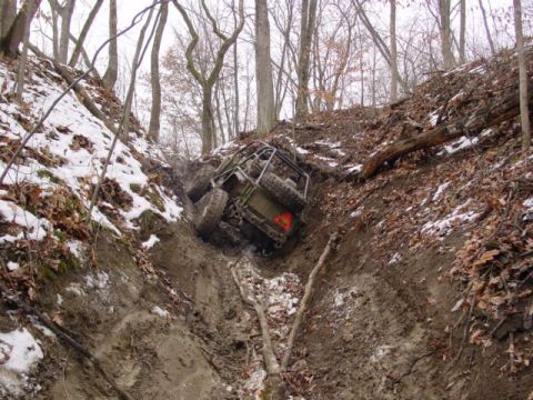 1992 Ford Bronco - An off-road vehicle is stuck in a steep, muddy ditch during winter conditions.