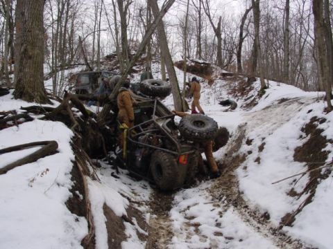 1992 Ford Bronco - Several people attempt to free an off-road buggy that has become stuck in a snowy ditch, with another vehicle partially visible behind it t…